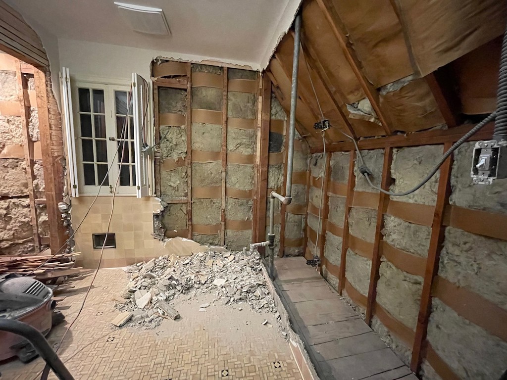 Demo of bathroom with torn tile and walls.