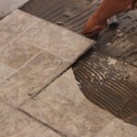 Homeowner loosening tile from floor.
