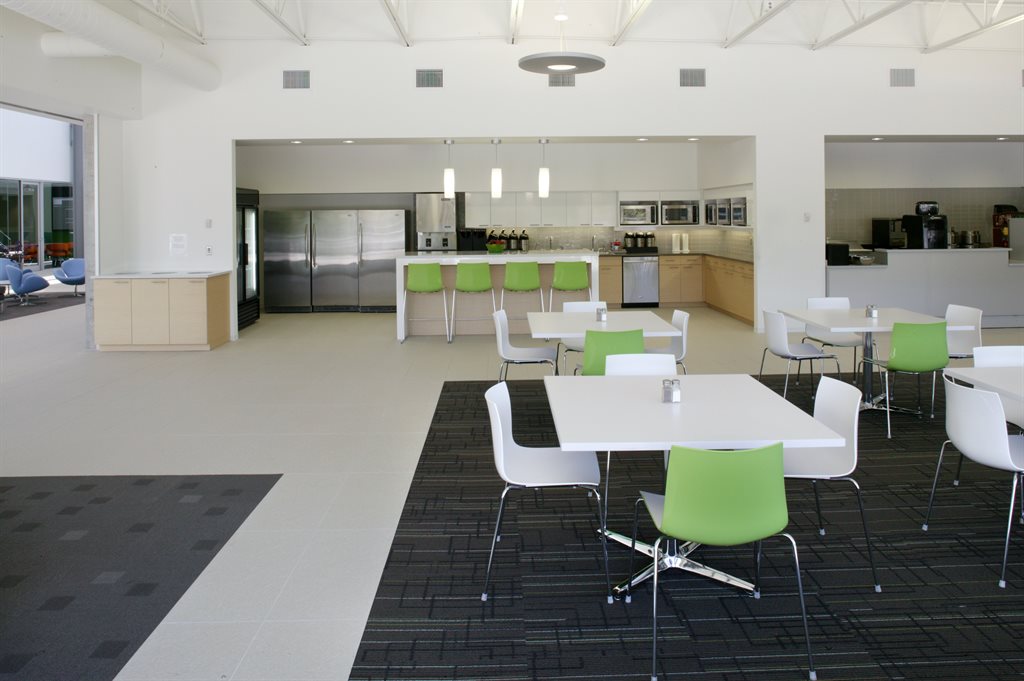A modern office cafeteria with seating and a kitchen