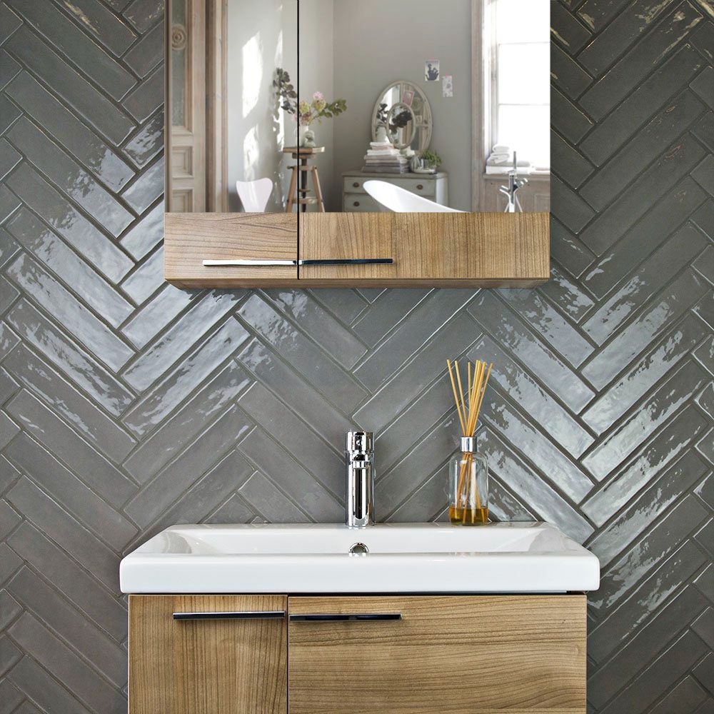 glossy slate colored subway tile backsplash behind a modern wooden bathroom sink