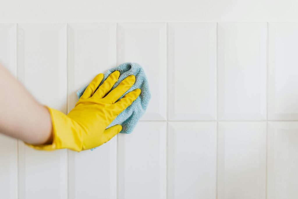 Person cleaning white tile with a cloth