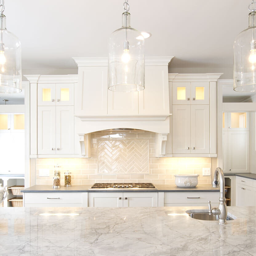 A white kitchen using stone and metal accents for contrast